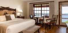 a bedroom with a bed, desk and chair next to a window that looks out onto the water