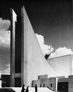 black and white photograph of two people standing in front of a large building with stairs