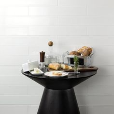 a black table topped with bread and other food on top of a white tiled wall