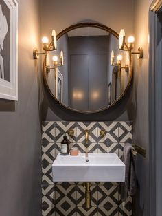 a bathroom sink sitting under a round mirror next to a wall mounted faucet