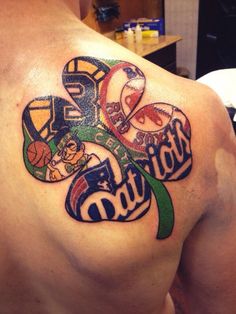 the back of a man's shoulder with tattoos on it and some sports related items