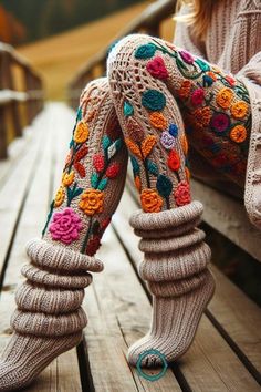 a woman sitting on top of a wooden bench wearing knitted socks and leg warmers