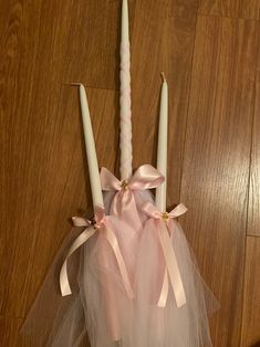 two candles with tulle and bows are on the floor