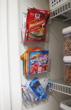 an open refrigerator door with food and snacks on the bottom shelf, along with other items