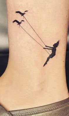 a woman's ankle tattoo with birds flying behind her