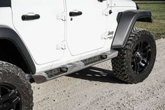 a white jeep parked on top of a gravel road