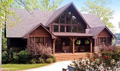 a large house sitting on top of a lush green field next to a forest filled with trees