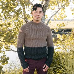 a man standing in front of a tree with his hands on his hips and looking at the camera