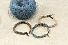 three bracelets are sitting next to a ball of yarn