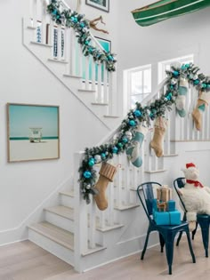 christmas stockings hanging from the banisters in a home decorated with blue and green ornaments