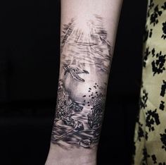 a woman's arm with a tattoo on it that has a turtle swimming in the water