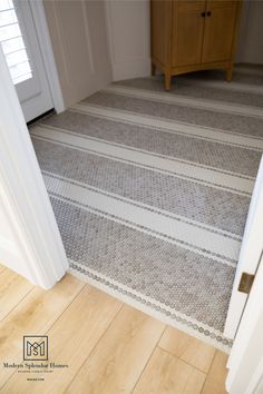 an open door leading to a white and gray striped carpet