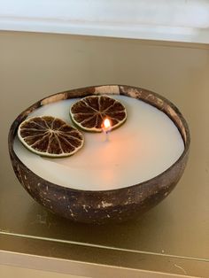 two grapefruits in a bowl with a lit candle