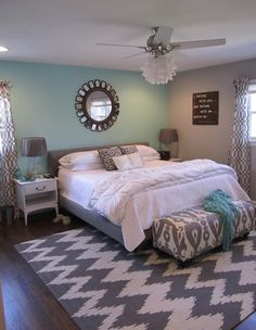 a bedroom with blue walls and white bedding in the center is decorated with gray and aqua accents