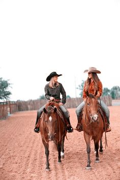 two women are riding horses in the dirt