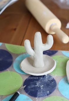 a clay cactus sitting on top of a table next to a rolling pin and glue