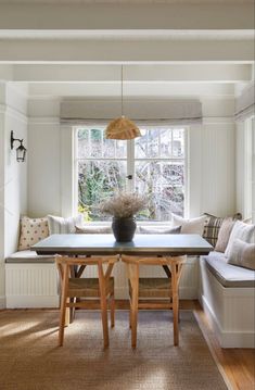 a dining room table and bench in front of a window with light coming through the windows