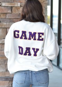 Soft sweatshirt features a sequin football on the front & “Gameday” patches on the back Collegiate Tops With Letter Embroidery For Game Day, Varsity Sweatshirt With Text Print, Collegiate Letter Embroidery Top For Game Day, White Top With Letter Patch For College, White Letter Patch Top For College, White College Top With Letter Patch, Game Day White Sweatshirt With Embroidered Graphics, White Game Day Sweatshirt With Embroidered Graphics, White Team Spirit Sweatshirt With Embroidered Graphics