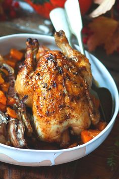 a close up of a chicken in a bowl with carrots and mushrooms on the side