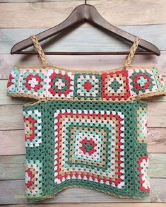 a crocheted top hanging on a wooden wall