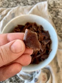 a hand holding a piece of chocolate in a bowl