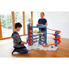 two boys playing with a toy set in the middle of a living room, and one boy is sitting on the floor