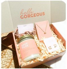 an open box containing a candle, necklace and gift card with the words gorgoeous on it