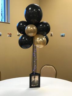 an arrangement of black and gold balloons in a vase