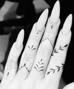 two fingers with tattoos on them, one has an arrow and the other has leaves