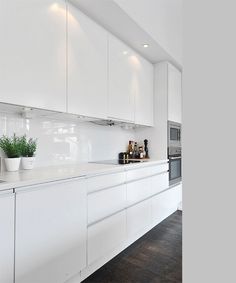 a kitchen with white cabinets and wooden floors