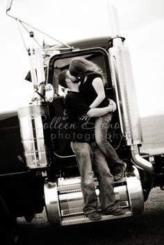 a man and woman kissing in the cab of a semi truck