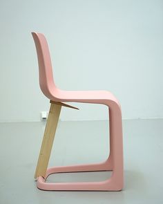 a pink chair sitting on top of a white floor next to a wooden stick sticking out of it's back