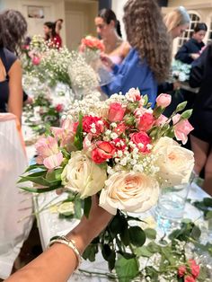 a bouquet of flowers is being held by a woman's hand at an event