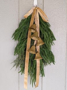 a christmas wreath hanging on the side of a door with bells and ribbon around it