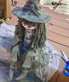 a statue of a woman with dreadlocks sitting on a wooden deck wearing a hat