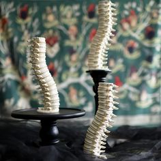 two black candlesticks with white bones on them sitting next to each other in front of a wall