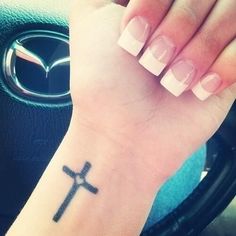 a woman's wrist with a cross tattoo on it