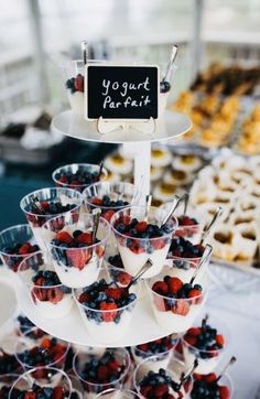 an assortment of desserts and pastries displayed on a table with a sign that says yogurt parfait