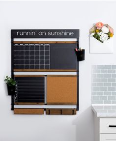 a bulletin board mounted to the wall next to a potted plant in a kitchen