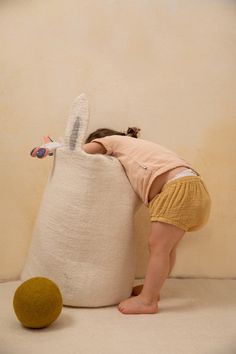 a small child is playing with a stuffed animal on the floor next to a ball