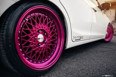 a white car with pink rims parked on the street