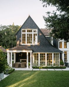 a house with white trim and large windows on the front door is surrounded by lush green grass