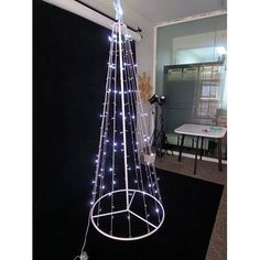 a white christmas tree with lights on it in the middle of a black carpeted room