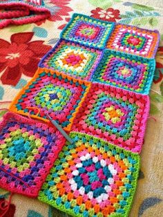 a crocheted blanket laying on the floor with scissors in it and some flowers