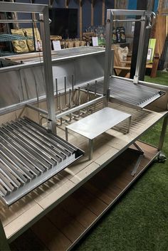 a stainless steel food cart sitting on top of a green grass covered floor next to a building