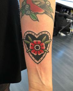 a tattoo on the arm of a person with a heart and flower in its center