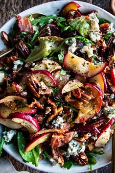 a salad with apples, blue cheese and pecans in it on a white plate