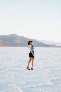 a woman standing in the middle of a salt flat