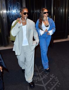 the man and woman are walking down the street together, one is wearing blue pants