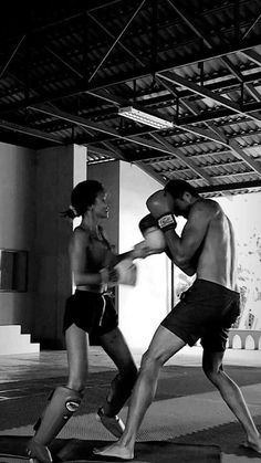 a man and woman are boxing in an indoor gym area with one punching the other's head